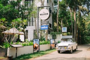 Beldon Boutique Hotel entrance in Hiriketiya, Sri Lanka, featuring a vintage white car, tropical palms, and modern architecture.